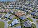 Aerial view of a community neighborhood and single Gathering home featuring mature landscaping and a neighborhood lake at 3330 Mayflower Loop, The Villages, FL 32163