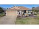 Single-story home featuring a beautifully landscaped yard, beige exterior, and a charming blue front door at 3330 Mayflower Loop, The Villages, FL 32163