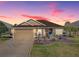 Charming single-story home with a meticulously landscaped yard and inviting blue front door set against a vibrant sky at 3330 Mayflower Loop, The Villages, FL 32163