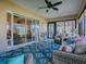 Bright sunroom with wicker furniture, patterned pillows, ceiling fan, and sliding glass doors to the backyard at 3330 Mayflower Loop, The Villages, FL 32163