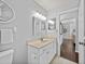 Well-lit bathroom with a granite vanity, decorative mirror, and an adjacent doorway at 3400 Foxboro Ct, Mount Dora, FL 32757