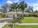 Well-maintained home featuring brick driveway, lush lawn, and beautiful palm trees at 3400 Foxboro Ct, Mount Dora, FL 32757