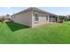 Well-maintained backyard with green lawn, neutral stucco siding, and louvered windows at 3540 O'Brien Pl, The Villages, FL 32163