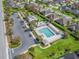 Overhead view of a community pool with lounge chairs, landscaping, a parking lot, and nearby homes at 3540 O'Brien Pl, The Villages, FL 32163