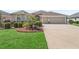 Lovely home featuring a well-manicured lawn, landscaping, and a spacious driveway leading to a two-car garage at 3540 O'Brien Pl, The Villages, FL 32163