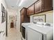 Laundry room with dark wood cabinets, white washer and dryer, and tile floor at 3540 O'Brien Pl, The Villages, FL 32163