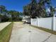 Long driveway leading to a two-car garage, complemented by a well-maintained yard and white vinyl fence at 390 Colonade Ct, Kissimmee, FL 34758