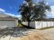 Side view showing a long driveway leading to a garage, with a privacy fence and mature tree at 390 Colonade Ct, Kissimmee, FL 34758