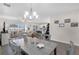 Open-concept dining area with modern chandelier, grey table and chairs, with easy access to the living room and kitchen at 3935 Fescue St, Clermont, FL 34714