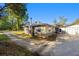 Side view of a single-story home with lush foliage and a gravel driveway at 39615 Forest Dr, Eustis, FL 32736