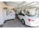 Well-organized garage with a white car, tool storage, and overhead lighting at 4036 Venetian Ln, The Villages, FL 32163