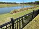 Backyard overlooking a pond with an iron fence and lush green grass at 511 Van Deen Pl, The Villages, FL 34762