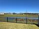 Scenic backyard view overlooking a tranquil pond, with a black metal fence for added privacy at 511 Van Deen Pl, The Villages, FL 34762