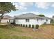 Exterior rear view of a white home featuring well-kept landscaping and a gray roof at 5332 Nw 20Th Pl, Ocala, FL 34482