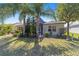 Well-kept backyard with palm trees, trimmed lawn, and a screened-in outdoor living space at 565 Brighton Dr, The Villages, FL 32162