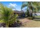 Landscaped backyard featuring a screened-in porch, palm trees, and tidy decorative rock at 565 Brighton Dr, The Villages, FL 32162