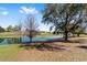 Scenic backyard with a pond and mature trees creating a serene outdoor space at 565 Brighton Dr, The Villages, FL 32162