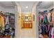 Hallway between dual closets leads to a well-lit bathroom with wood vanity at 565 Brighton Dr, The Villages, FL 32162