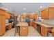 Kitchen with wooden cabinets, black appliances, an island, and tile flooring at 565 Brighton Dr, The Villages, FL 32162