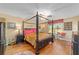 Main bedroom with hardwood floors, a four-poster bed, and natural lighting at 565 Brighton Dr, The Villages, FL 32162