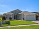 Inviting single-story home with brick driveway, two-car garage, manicured lawn, and front-facing bay windows at 5718 Illumination Ln, Leesburg, FL 34748