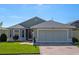 Charming single-story home featuring a brick driveway, two-car garage, manicured lawn, and meticulous landscaping at 5718 Illumination Ln, Leesburg, FL 34748