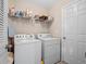 Functional laundry room with washer, dryer, overhead shelving, and a utility sink at 5718 Illumination Ln, Leesburg, FL 34748