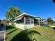 Inviting home featuring an enclosed porch, mature landscaping, and a well-maintained lawn at 607 Webb Way, The Villages, FL 32159