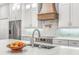 Close-up of a kitchen island featuring a sink, marble countertops, and a custom range hood at 6206 Ocilla Loop, Clermont, FL 34714