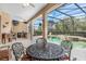 Outdoor living space showcasing a screened-in pool with a spa, dining area, and outdoor kitchen at 6206 Ocilla Loop, Clermont, FL 34714