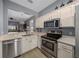 Bright kitchen features stainless steel appliances and white cabinetry, overlooking the living room at 906 Calabria Ave, Davenport, FL 33897