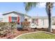 Single-story home featuring well-manicured lawn, vibrant foliage, front-facing garage and a welcoming red front door at 9511 Se 168Th Elderberry Pl, The Villages, FL 32162