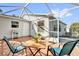 The screened patio has tiled flooring, a table, two chairs, and access to the home's back door at 9511 Se 168Th Elderberry Pl, The Villages, FL 32162