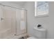 Bright bathroom featuring an enclosed shower stall, a white toilet, and a window with natural light at 9511 Se 168Th Elderberry Pl, The Villages, FL 32162