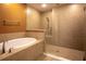 Bright bathroom showcasing a soaking tub, a glass-enclosed shower, and neutral tone tiles at 1041 Bradford Ridge Dr, Leesburg, FL 34748