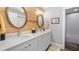 Bathroom with double vanity, framed mirrors, natural wood accent wall, and tiled shower at 12117 Cypress Ln, Clermont, FL 34711