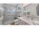 Bright bathroom with glass shower, wood look tile, and white cabinets at 12117 Cypress Ln, Clermont, FL 34711