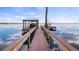 Long wood plank dock with a boat house at the end, set against a tranquil lake with reflections of the sky at 12117 Cypress Ln, Clermont, FL 34711