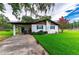 Exterior view of a well-kept single-story home with blue shutters, a concrete driveway, and a vibrant green lawn at 132 E Belt Ave, Bushnell, FL 33513