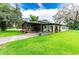 Charming single-story home featuring a screened porch, covered parking, and vibrant flower decorations on a spacious lawn at 132 E Belt Ave, Bushnell, FL 33513