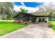 Inviting single-story home with a screened porch and covered parking area, surrounded by a lush green lawn at 132 E Belt Ave, Bushnell, FL 33513