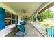 Spacious covered front porch featuring wicker furniture, ceiling fans, and views of the yard at 132 E Belt Ave, Bushnell, FL 33513