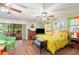 Bright main bedroom with wood floors, ceiling fan, sliding door to lanai and a yellow comforter at 132 E Belt Ave, Bushnell, FL 33513