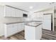 Well-lit kitchen with granite countertops, a kitchen island, and white cabinetry at 13877 County Road 109F, Lady Lake, FL 32159