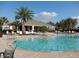 Relaxing community pool with lounge chairs, palm trees, and a clear blue sky, adjacent to a clubhouse and deck at 1408 Diamond Loop Dr, Kissimmee, FL 34744