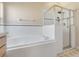 A close-up view of the bathtub with tiled walls and glass enclosed shower in a well-lit bathroom at 16839 Rockwell Heights Ln, Clermont, FL 34711