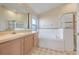 Well-lit bathroom featuring a vanity, soaking tub with tile surround, and glass-enclosed shower at 16839 Rockwell Heights Ln, Clermont, FL 34711