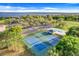 Aerial view featuring community amenities including tennis courts, a pool, and parking near the lake at 16839 Rockwell Heights Ln, Clermont, FL 34711