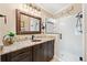 Modern bathroom with a granite countertop vanity, a framed mirror, and a glass-enclosed shower at 17126 Se 78Th Larchmont Ct, The Villages, FL 32162