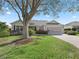 Inviting single-story home with a manicured lawn, mature trees, and a convenient two-car garage at 17635 Se 82Nd Annadale Ter, The Villages, FL 32162